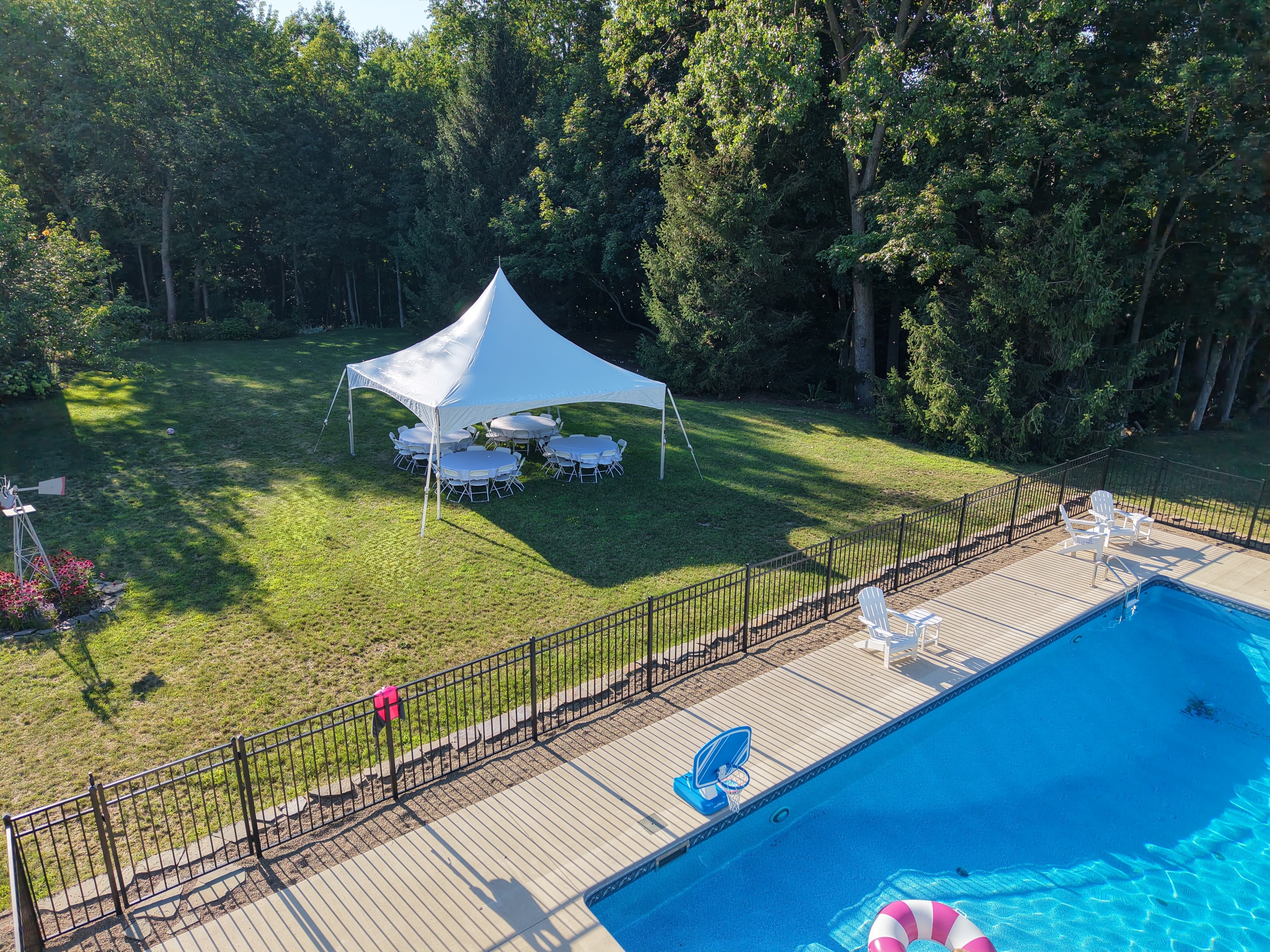 High peak tent setup beside backyard pool